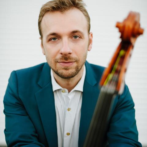 Man holding cello while wearing a blue suit