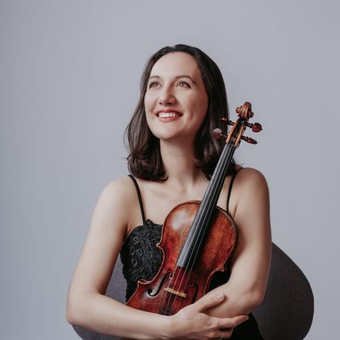 A woman is seated with a violin on her lap