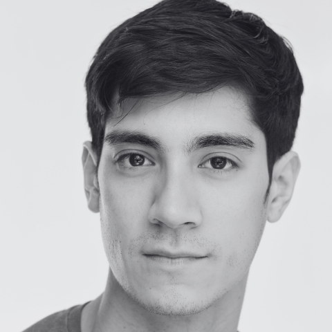 Close cropped black and white photo of man smiling slightly at camera