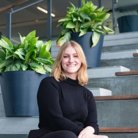 Woman sitting on stairs wearing all black smiling at camera